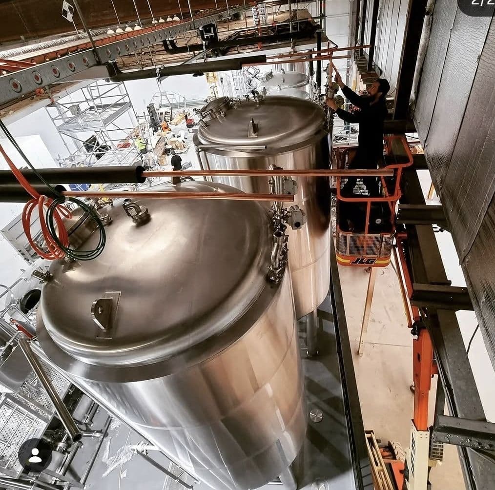 Technician working on brewery tanks and glycol cooling equipment